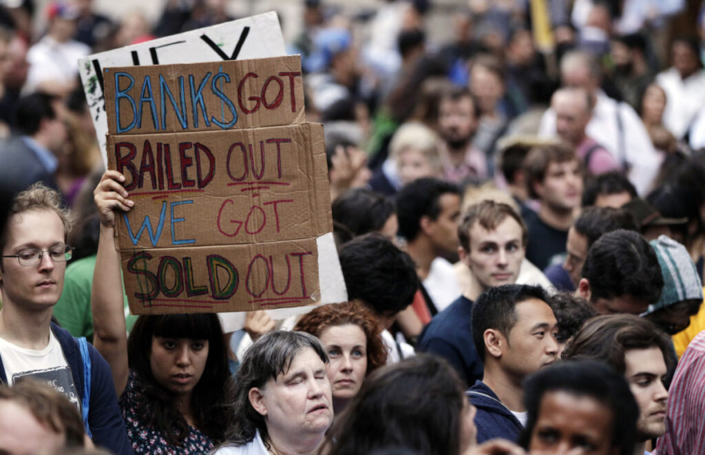 A demonstrator from the Occupy Wall Street campaign holds aloft a sign as the march enters a courtyard near the New York Police Department headquarters in New York September 30, 2011. Protesters who have camped out near Wall Street for two weeks gathered on Friday to march to police headquarters over what they viewed as excessive force and unfair treatment of minorities and Muslims.The Occupy Wall Street movement, whose members have vowed to stay through the winter, are protesting issues including the 2008 bank bailouts, foreclosures and high unemployment. More than 500 people were gathered ahead of the start of the planned late afternoon march to One Police Plaza, the center of police operations, in downtown Manhattan.