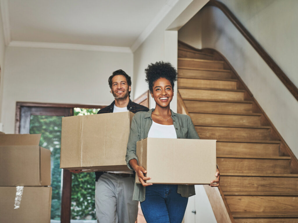 A couple carrying boxes while moving into a new house